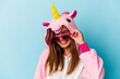 Young woman wearing an unicorn costume with sunglasses isolated