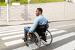 Young disabled black man in wheelchair using crosswalk outdoors. Quality of life and impairment concept
