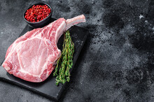 Raw Fresh Tomahawk Pork Chop Steak On A Marble Board. Black Background. Top View. Copy Space