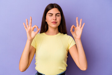 Wall Mural - Young caucasian woman isolated on purple background relaxes after hard working day, she is performing yoga.