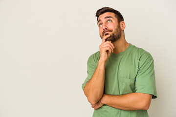 Wall Mural - Young caucasian man isolated on white background relaxed thinking about something looking at a copy space.