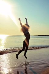 Wall Mural - child jumping on the beach at sunset