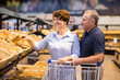 © caftor - Elderly couple buys bread and baking in grocery section of supermarket