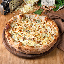 Four Cheese Pizza or Quattro Formaggi Pizza topped with tomato sauce, mozzarella, gorgonzola, Parmigiano Reggiano, and goat cheese. Rustic style pizza layout.