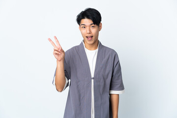 Young Chinese man isolated on white background smiling and showing victory sign