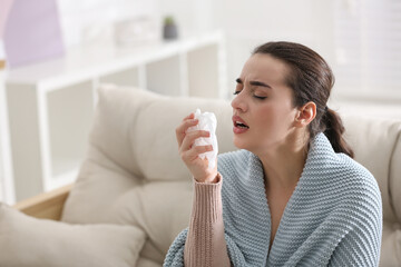 Canvas Print - Young woman suffering from runny nose in living room