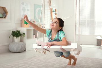 Poster - Cute little girl playing on swing at home