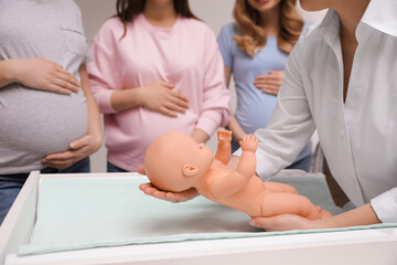 Canvas Print - Pregnant women learning how to swaddle baby at courses for expectant mothers indoors, closeup