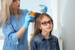 © New Africa - Doctor using nit comb and spray on girl's hair indoors. Anti lice treatment