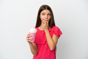 Wall Mural - Little girl with strawberry milkshake over isolated white background having doubts and thinking