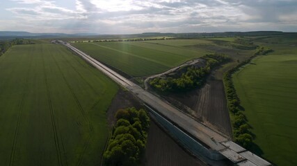Wall Mural - drone flight over beautiful nature with green rolling fields and a newly built highway that passes t