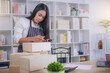 © Panumas - Startup on-line business entrepreneur SME, Woman packing product in box and working with paperwork at home office. SME e-commerce telemarketing concept