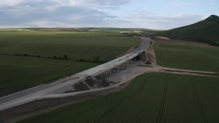 Wall Mural - drone flight over beautiful nature with green rolling fields and a newly built highway that passes t