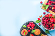 © ricka_kinamoto - Summer baking concept, homemade vanilla white muffins with berry - strawberry, cherry, and mint, on baking sheet, light blue background top view copy space