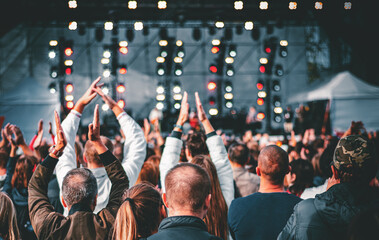 many different people at a concert listening to rock band music open air