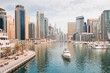© EdNurg - The boat sails along the canal in the Dubai Marina area against the backdrop of numerous residential skyscrapers and hotels