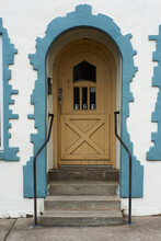 Yellow Door With Stairs On A Old White Building With Blue Trim.