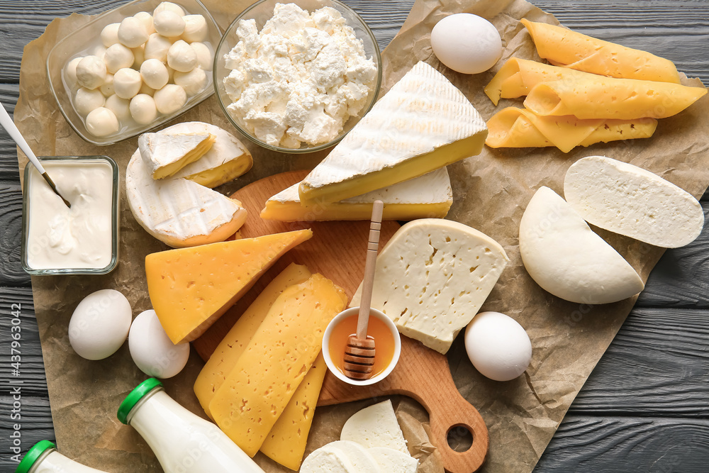 Different dairy products, chicken eggs and honey on dark wooden background