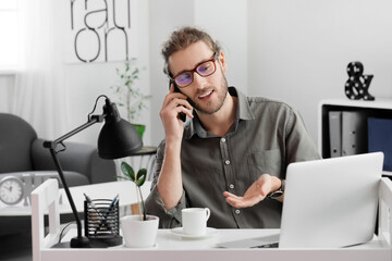 Canvas Print - Handsome young man talking by mobile phone in office