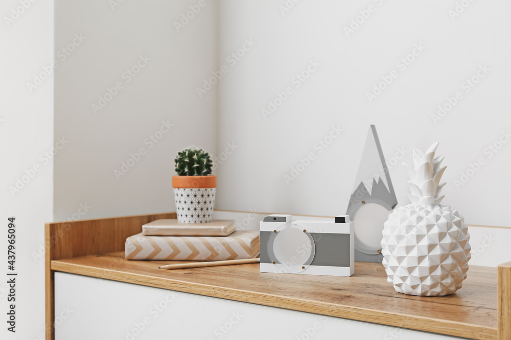 Stylish decor and houseplant on shelf near light wall