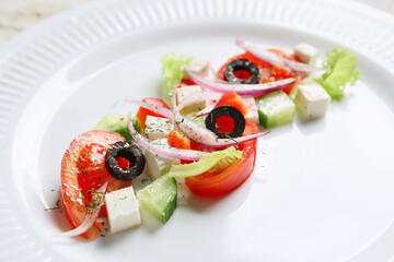 Plate of tasty Greek salad on wooden table, closeup