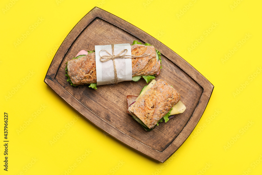 Board with tasty ciabatta sandwiches on color background