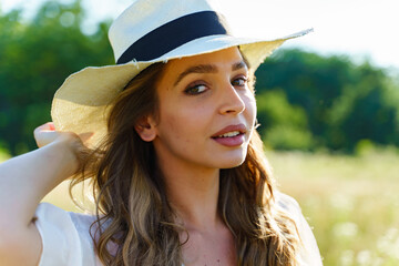 Side view close up portrait of beautiful young caucasian woman wearing hat in summer day in the field with eyes closed daydreaming