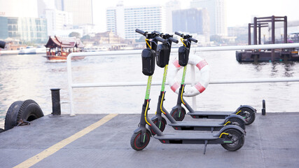 E-scooter parking at pier near river. New generation friendly eco and green energy of electric 2 wheels transportation in traffic city.