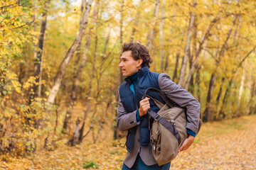 Tall handsome man with a bag in the autumn alley