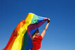 © Aleksandra Iarosh - girl with lgbt flag behind her back against a bright blue sky