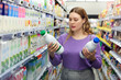 Portrait of smiling glad pleasant positive woman holding bottle with fresh milk in grocery shop