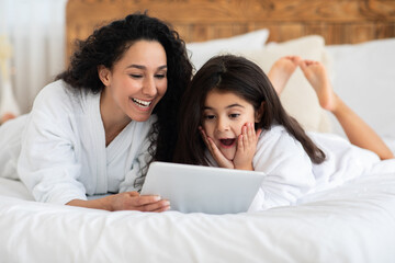 Wall Mural - Emotional mom and little girl laying on bed with pad