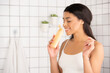 smiling young african american woman in white tank top smelling aroma of shower gel in bathroom