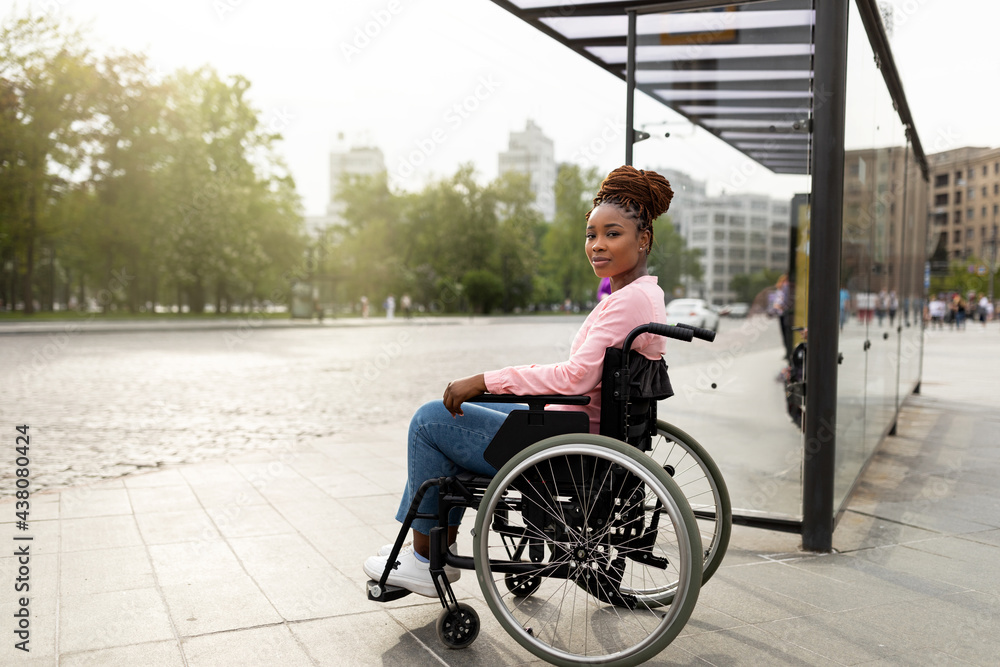 Young black handicapped woman in wheelchair cannot board vehicle suitable for impaired persons, waiting on bus stop - obrazy, fototapety, plakaty 