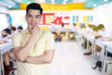 Wall Mural - Portrait handsome young asian man wearing a yellow shirt happy smile isolated on background blurred student study in class at school. Education concept.