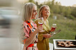 © Johnér - Female friends holding wine glasses and barbecuing meat