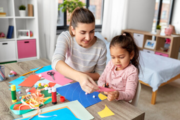 Wall Mural - family, art and craft concept - mother spending time with her little daughter with glue making applique of color paper at home