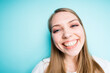 © DmitryStock - Happy girl with long hair smiling broadly looking at the camera while standing on a blue background