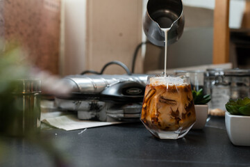 Wall Mural - Barista pouring milk into a glass of iced coffee