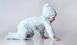© FAB.1 - Active creeping child with concentrated reproduction of the face. Little child in a blue cotton suit with a hat. Growth of a newborn baby, development and study of the environment.