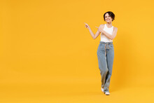 Full Length Smiling Young Woman 20s With Bob Haircut Wearing White Tank Top Shirt Walking Go Point Index Finger Aside On Workspace Area Mock Up Isolated On Yellow Background People Lifestyle Concept.