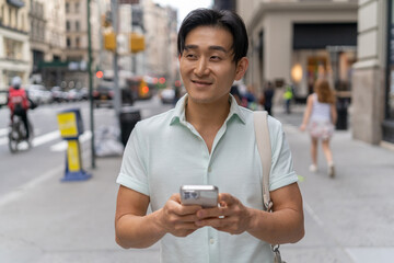 Sticker - Young Asian man in city walking using cellphone