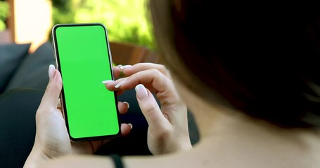 Wall Mural - the girl scrolls the smartphone green screen in the garden - reading something on a mobile phone tem