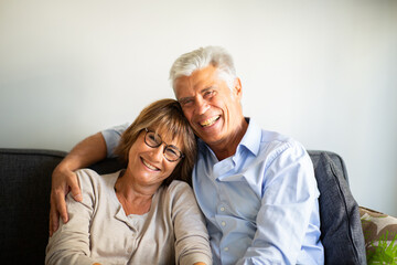 Wall Mural - Close up smiling happy older couple sitting on sofa together