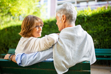Wall Mural - behind older couple sitting on park bench
