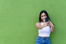 Smiling Teen Taking Selfie On Smartphone On Green Background