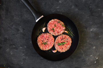 Poster - Raw beef meat burger steak cutlets in the pan on the black table.