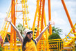 © chokniti - a women has fun happy joy day at amusement park in summer sunny day, roller coaster, jumping girl, vacation leisure holiday, activities concept. asian women, nice clear blue sky. enjoy moment