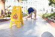 Man falling on tile near sign with inscription caution wet floor closeup