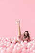 © GVS - Funny smiling woman lying in many pink balloons with her legs up